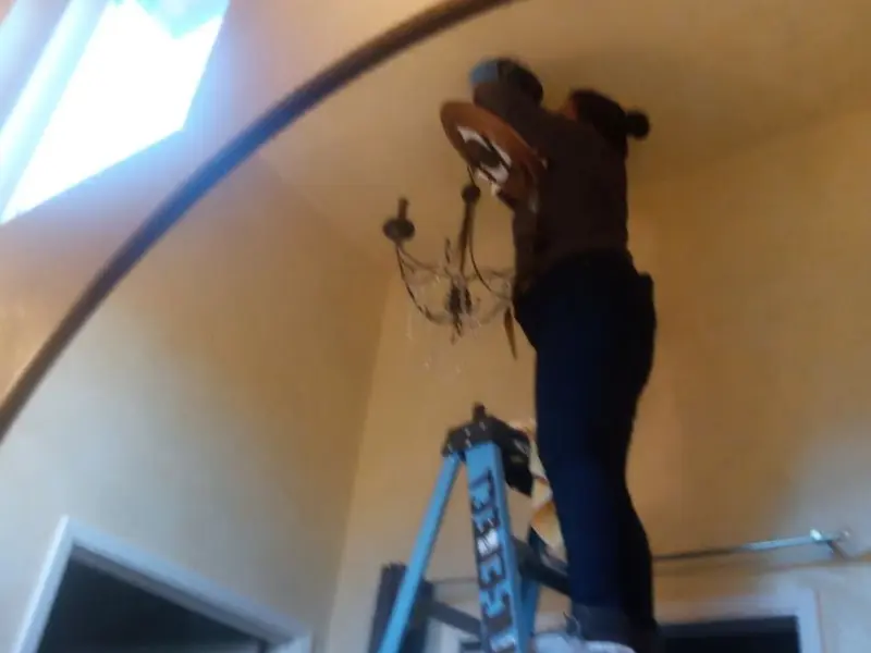 Electrician installing a chandelier in a Fredericksburg residence
